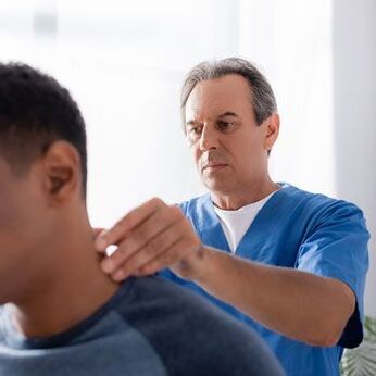 A doctor performs a diagnostic exam on a patient suffering from neck pain.